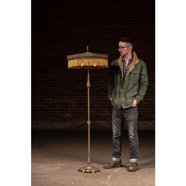 Cast metal floor lamp featuring a slender, twisted column with cast decorative nodes and an ornate openwork base. The...