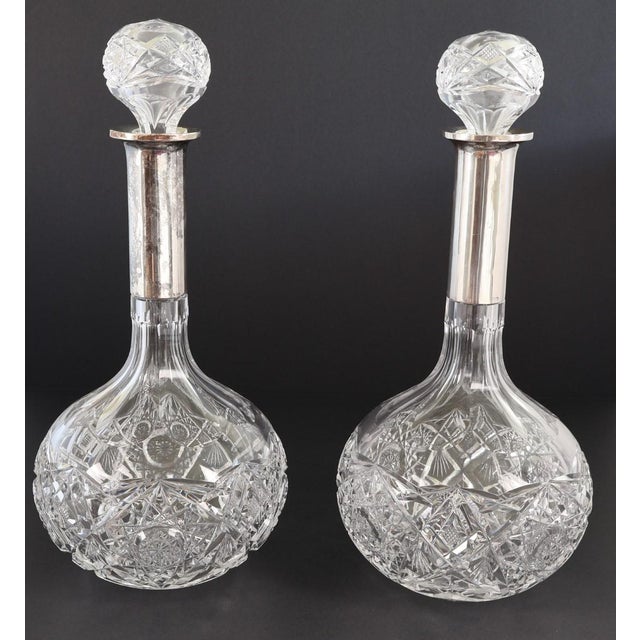 A refined pair of antique cut crystal decanters featuring substantial 880 silver collars and matching cut crystal...