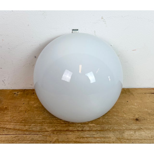 Vintage wall light made in former Czechoslovakia during the 1960s. It featutes an iron wall mounting and a milk glass...