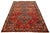 This beautiful handmade wool rug features a red field with navy blue and orange in a tribal design. This rug measures...