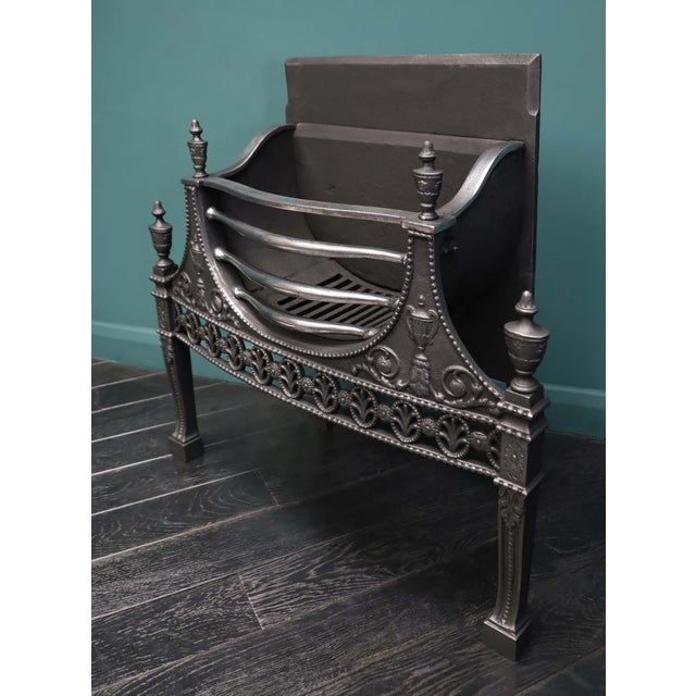 An elegant 19th century Wwought & cast fire grate in the earlier Neo-Classical Manner. A semi-circular fire basket with...