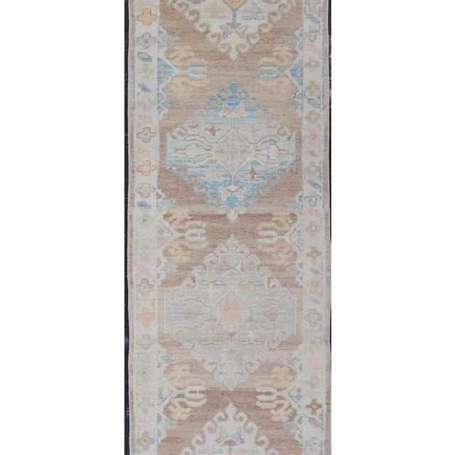 Measures: 3'0 x 20'8 Long Turkish Oushak Runner with Pale Blue, Soft Yellow, and Light Brown Motifs. Keivan Woven Arts....