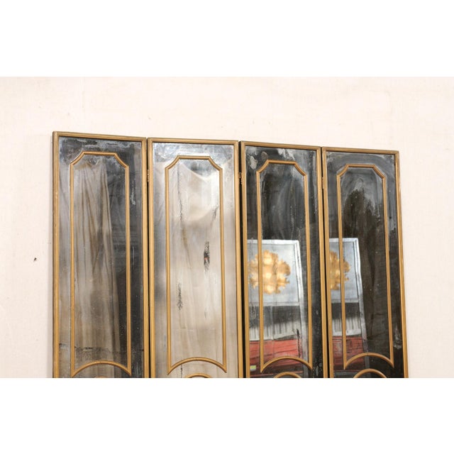 A French mid-century antiqued glass and gold folding screen, circa 1950's. This vintage room divider from France features...