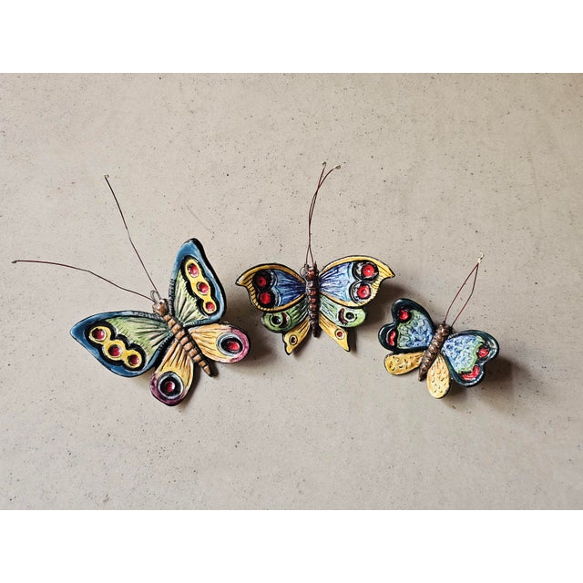 This set of three ceramic butterflies features wire antennae and a hook for wall hanging. Hand-painted in bright colors...
