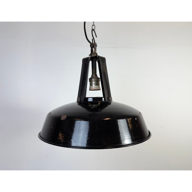This industrial lamp was made by mazda in france during the 1960s. It features a black enamel shade with white enamel...