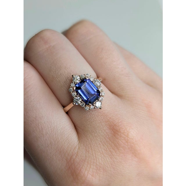 A tanzanite sits in a deep violet-blue at the centre of this solid 14K rose gold ring, surrounded by sixteen earth-mined...