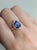 A tanzanite sits in a deep violet-blue at the centre of this solid 14K rose gold ring, surrounded by sixteen earth-mined...