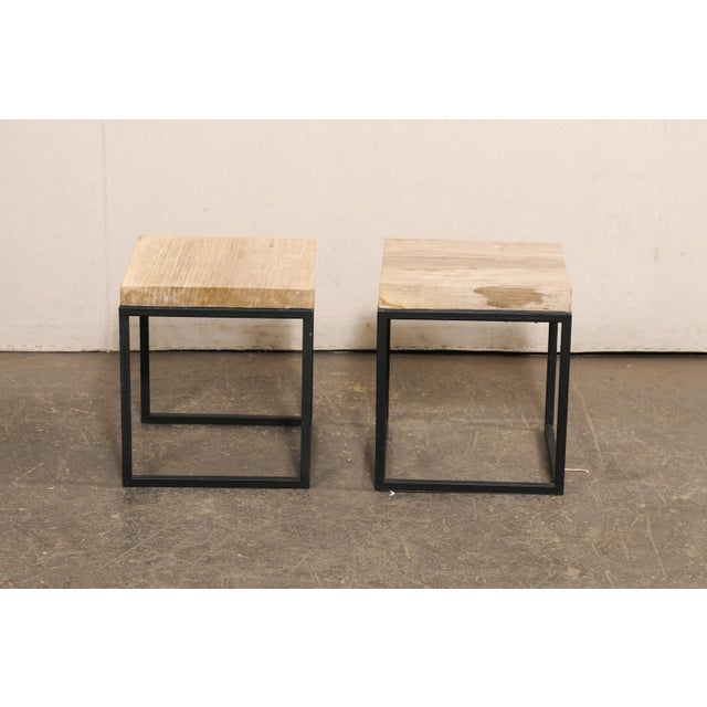 A pair of modern style custom petrified wood top side tables. This pair of tables each feature a square-shaped petrified...