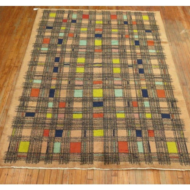 A handmade midcentury Turkish retro style rug with a square thin line repetitive design in multiple colors on a pink-bone...