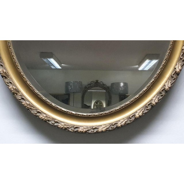 Offered for sale is this bevelled edge Edwardian antique oval gilt mirror with oak leaf detailing.