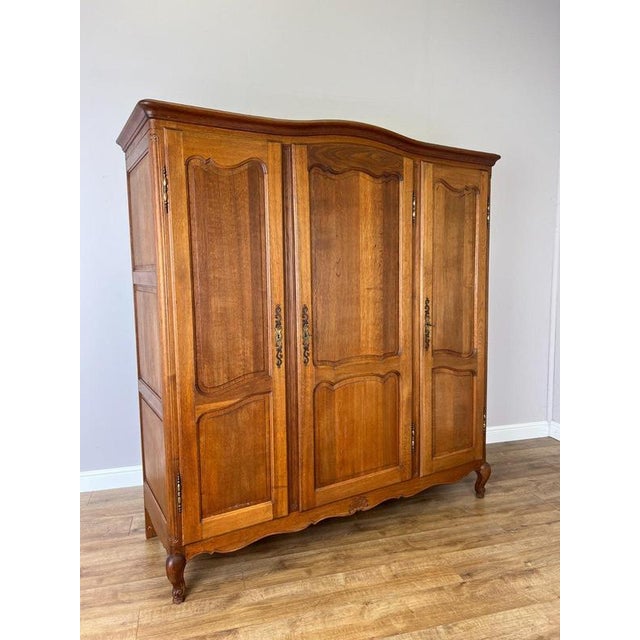 An elegant Vintage French Louis wardrobe in oak, featuring three beautifully shaped panelled doors, a sweeping curved top...