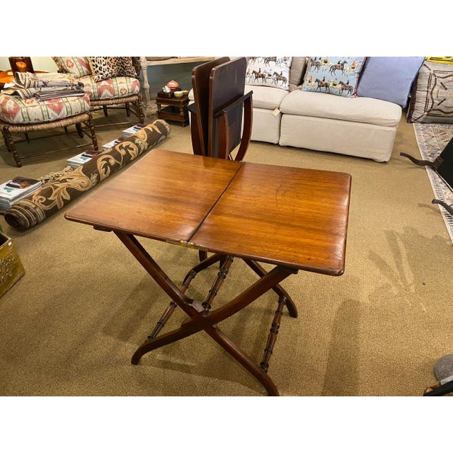 A antique English Regency mahogany coaching table from the mid 19th century featuring a center-folding rectangular top....