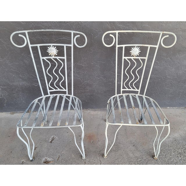 A pair of iron patio chairs. Substantial iron frames with a cast iron "Sun" detail. Each measure: 37.75 inches high. 22...