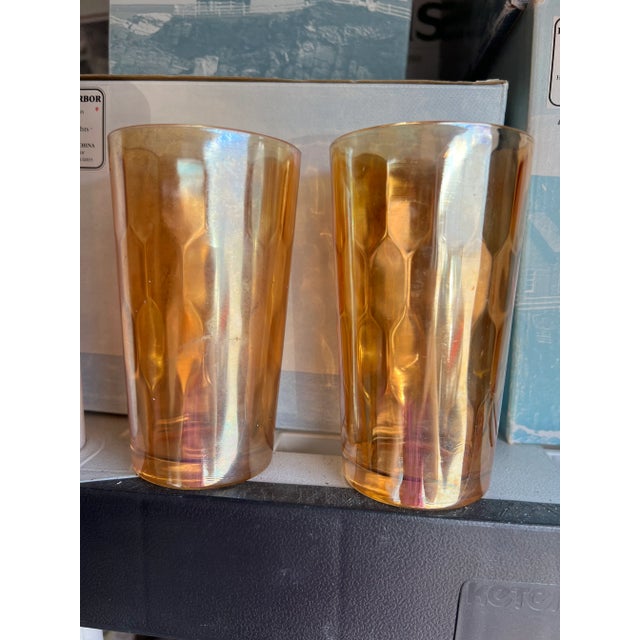 Jeannette glass tumblers, marigold iridescent color, hex optic or honeycomb optic pattern. They're about 5" tall. The rim...