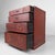 A compact Japanese drawer cabinet with four drawers, a deep reddish-brown colour and decorative floral motifs in relief....