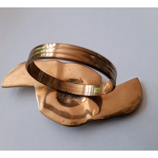 Set of eight solid brass napkin rings. In the shape of a rose floral with leaves on both ends. Nice weight and very good...