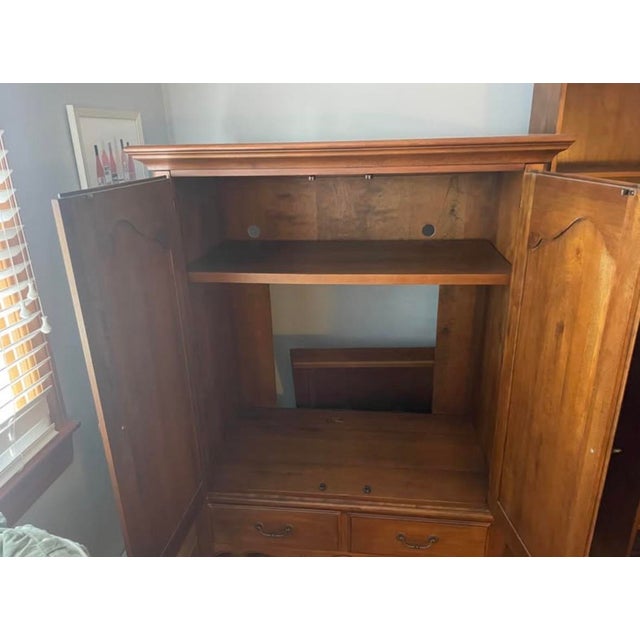 Sturdy wood armoire from the Ethan Allen Country French collection. This piece has a warm brown finish with ornate brass-...