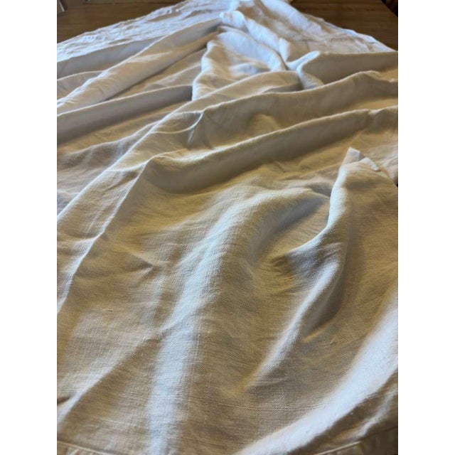 A beautifully soft and character-filled antique French linen sheet, featuring delicate red cross-stitch monograms that...