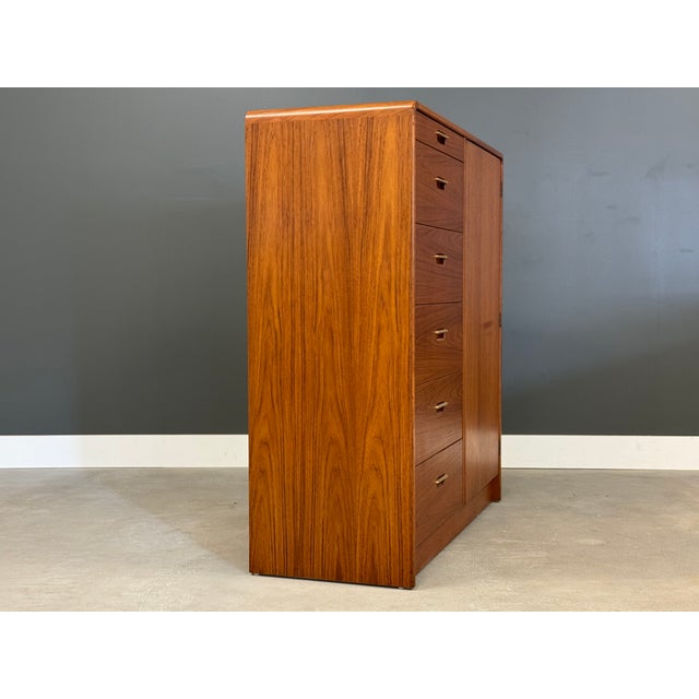 A mid century modern teak armoire dresser with brass drawer pulls. Push to open door. Made in Denmark. 45.5” wide. 18”...