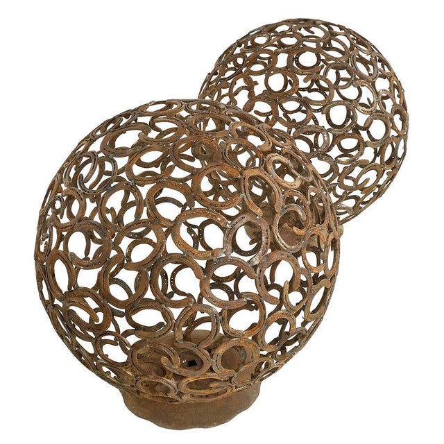 Handcrafted by a master ironworker, these two imposing spheres are made up of a tangle of horseshoes welded together....