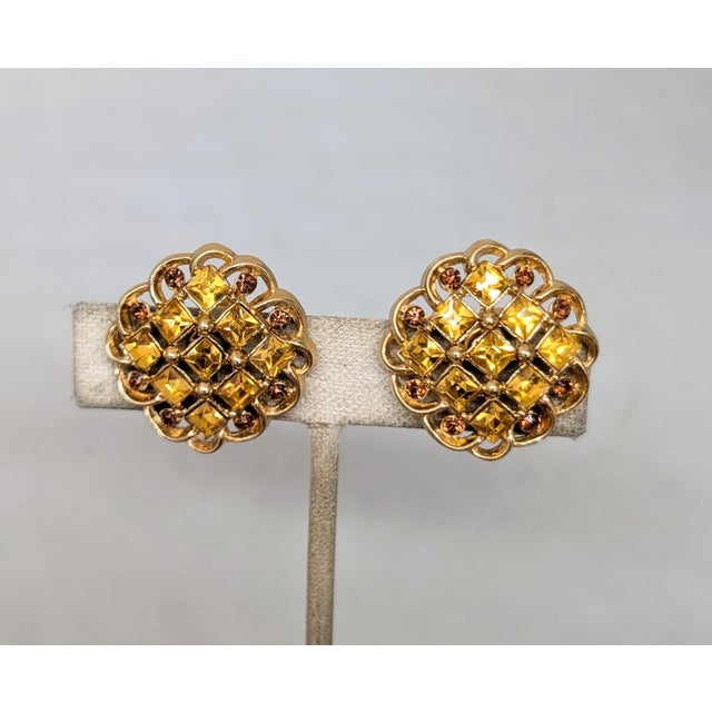 1960s goldtone square cut faux-citrines with small round faux-topaz accents clip earrings. Marked crown "TRIFARI ©" on the...