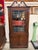 Elegant mahogany corner display cabinet featuring an ornate broken-scroll pediment, geometric astragal glass door, and...