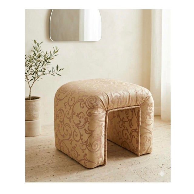 A sculptural vintage waterfall vanity stool featuring a continuous curved profile and fully upholstered pastel pink-and-...