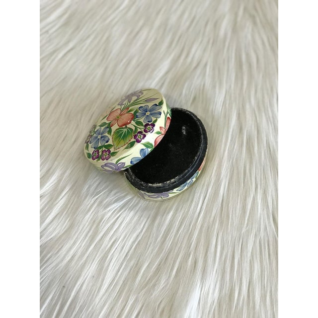 A vintage, oval-shaped, lidded lacquer box with black interior and intricately painted blue, pink, and purple floral...
