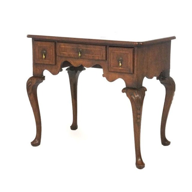 An antique English Queen Anne low boy offers mahogany construction with shaped top over case having three drawers, raised...