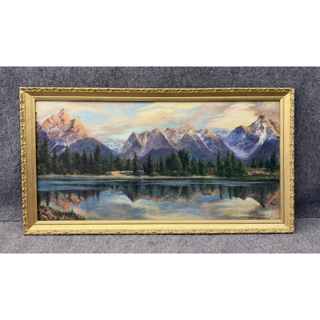 This original 1968 oil on board by Lillian Lewis depicts a tranquil mountain range reflected in a still lake, with layered...
