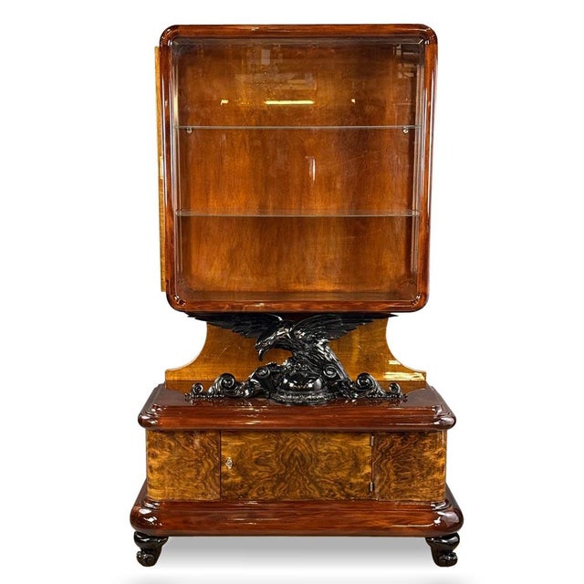 A striking Art Deco display cabinet featuring a unique sculptural eagle element forming the central connection between the...