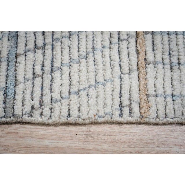 This hand knotted pile rug is crafted from wool and features a primary color palette of ivory, beige, cream, and white....