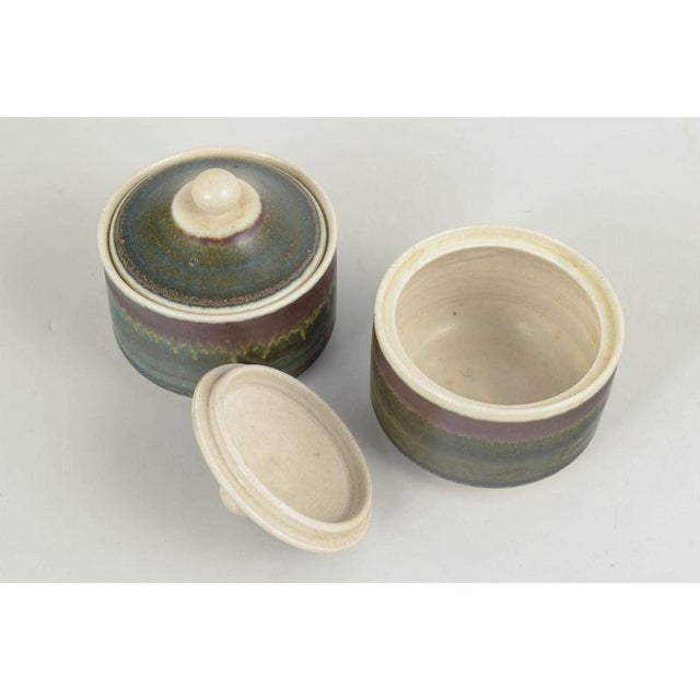 John Andersson for Höganäs, pair of lidded jars. Pair of thrown stoneware lidded jars with cylindrical bodies and fitted...