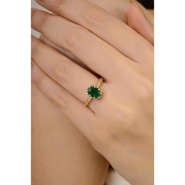This vintage style ring is crafted in 14k yellow gold, showcasing a 1.23-carat oval cut emerald at the center. Surrounding...