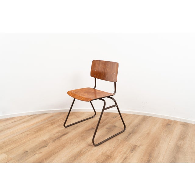 Model Kwartet industrial chair by Marko. The chair has a wooden seating and backpiece on a brown coated tubular metal...