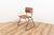 Model Kwartet industrial chair by Marko. The chair has a wooden seating and backpiece on a brown coated tubular metal...