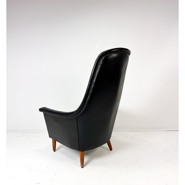 Mid-Century Scandinavian Modern Black Leather High-Back Lounge Chair. Sculptural high back with gently curved armrests...