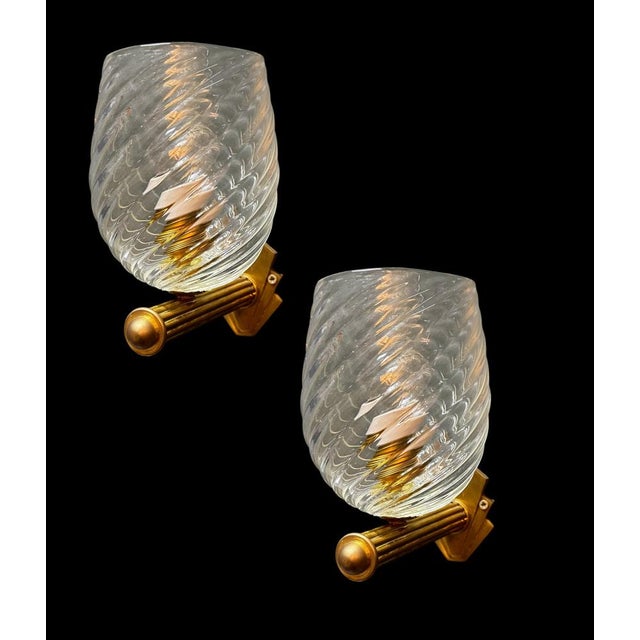 Elegant set of two vintage-style wall sconces featuring hand-crafted Murano glass shades mounted on warm brass supports....