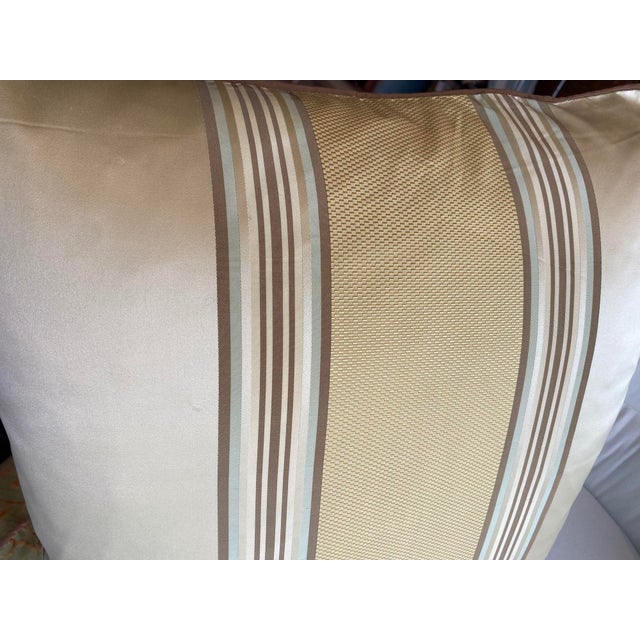 The front of this pillow features a sophisticated arrangement of wide and narrow stripes in neutral shades of gold, brown,...