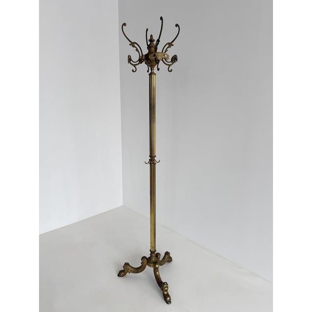Elegant vintage brass coat rack featuring a rotating crown, decorative cast brass detailing, a fluted column, and a...