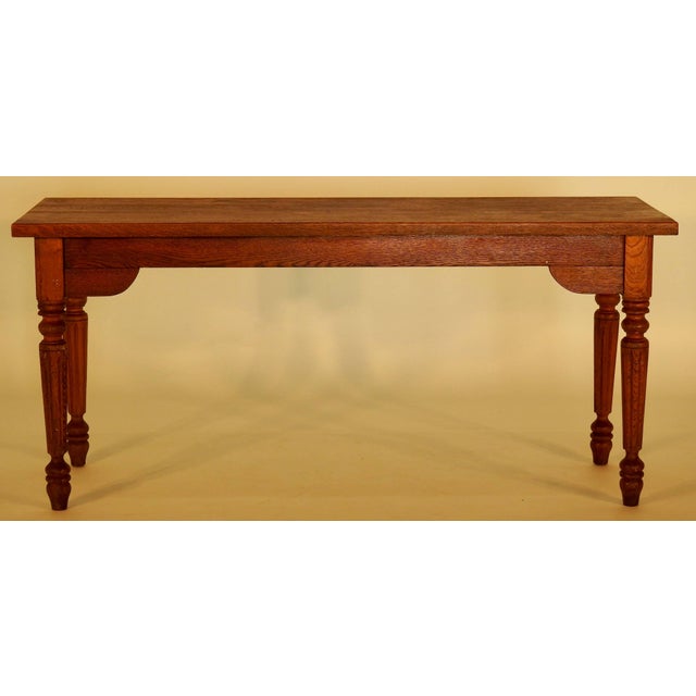 A walnut entry table featuring a rectangular surface, straight aprons with curved quarter panels and rests on four turned...