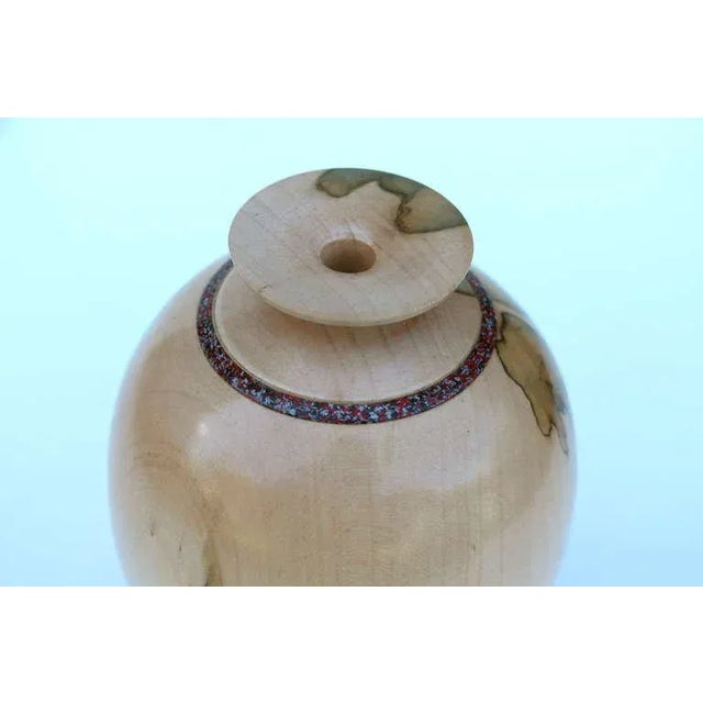 A beautiful hand-turned maple vessel signed on the base Jill Johnston N245 3-99 and maple. It has a ring of inlaid...