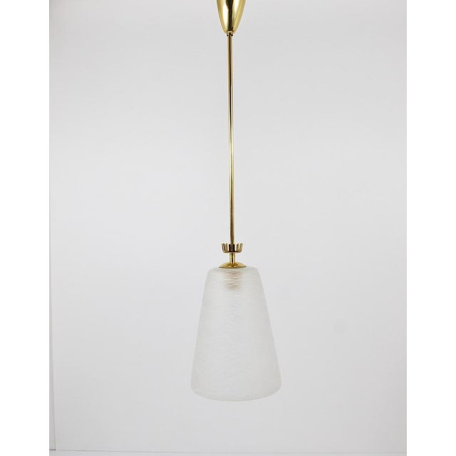 A charming Italian modernist ceiling light from the 1950s. Made of polished brass, it has a conical satined lampshade with...