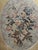 Elegant woven floral tapestry wall hanging featuring a lush central bouquet tied with a striped ribbon and framed within...