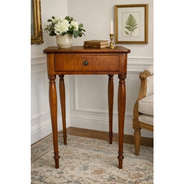 Beautiful vintage solid wood side table featuring elegant turned legs, a single drawer, and rich warm wood grain. Likely...