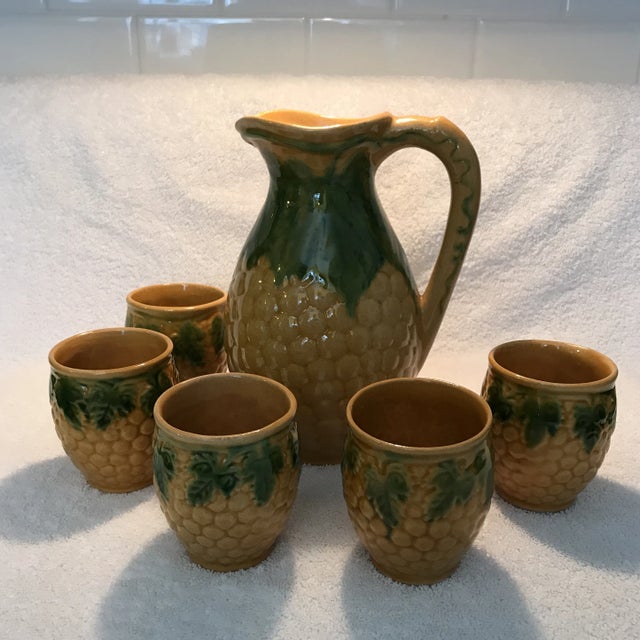 Vintage ceramic set, beautiful pitcher decorated with grapes and green leaves against a golden background. Perfect for...