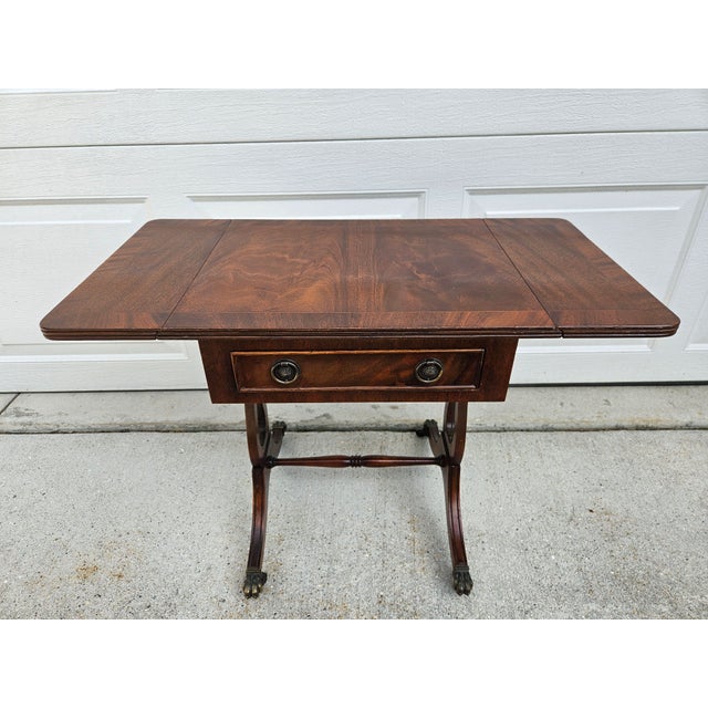 A beautiful lyre-based side table with one drawer and a banded crotch mahogany top. This piece is on clawfoot casters and...