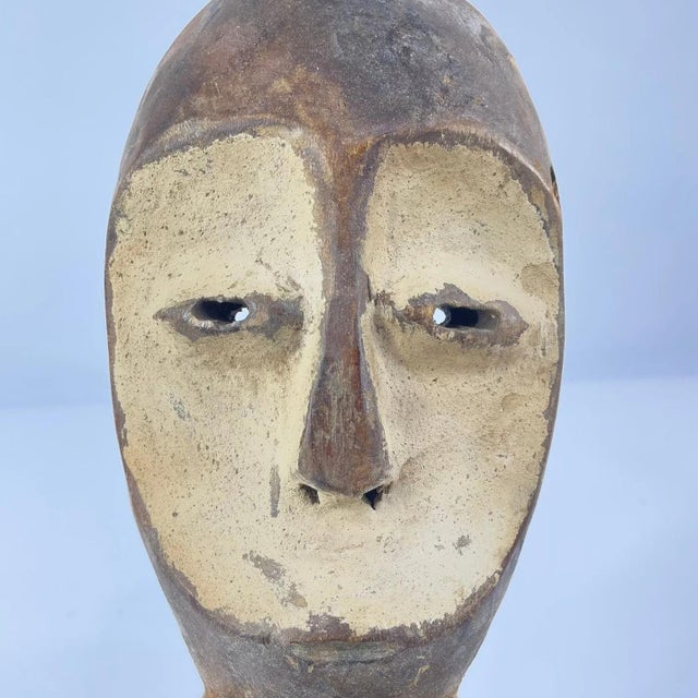 Lega masks, wooden and featuring elongated faces with a central ridge, almond-shaped eyes, and symbolic geometric...