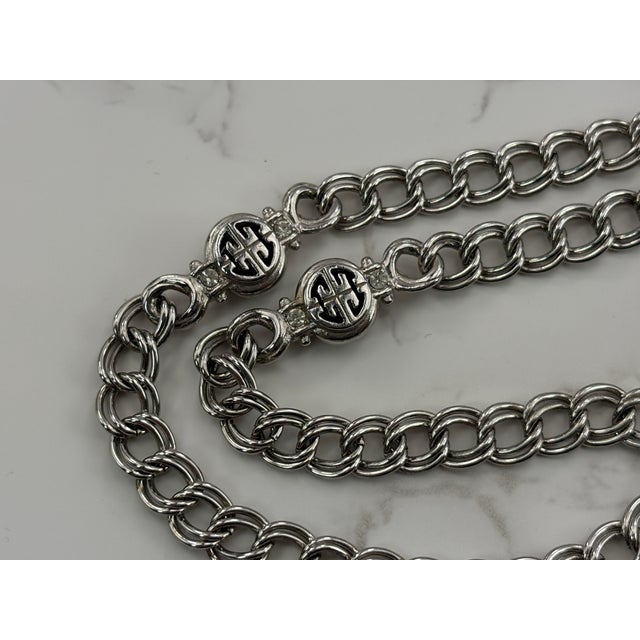 A classic vintage Givenchy logo station necklace in silver tone metal, accented with clear rhinestones for subtle sparkle....