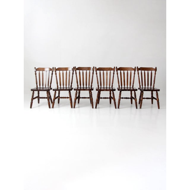 Set of six vintage spindle back dining chairs with turned legs, sculpted seats, and a warm wood tone that feels classic...